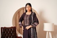 Portrait of a woman in a traditional Pakistani dress with elegant jewelry, indoors.